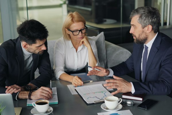 Three colleagues reviewing figures together in a meeting.